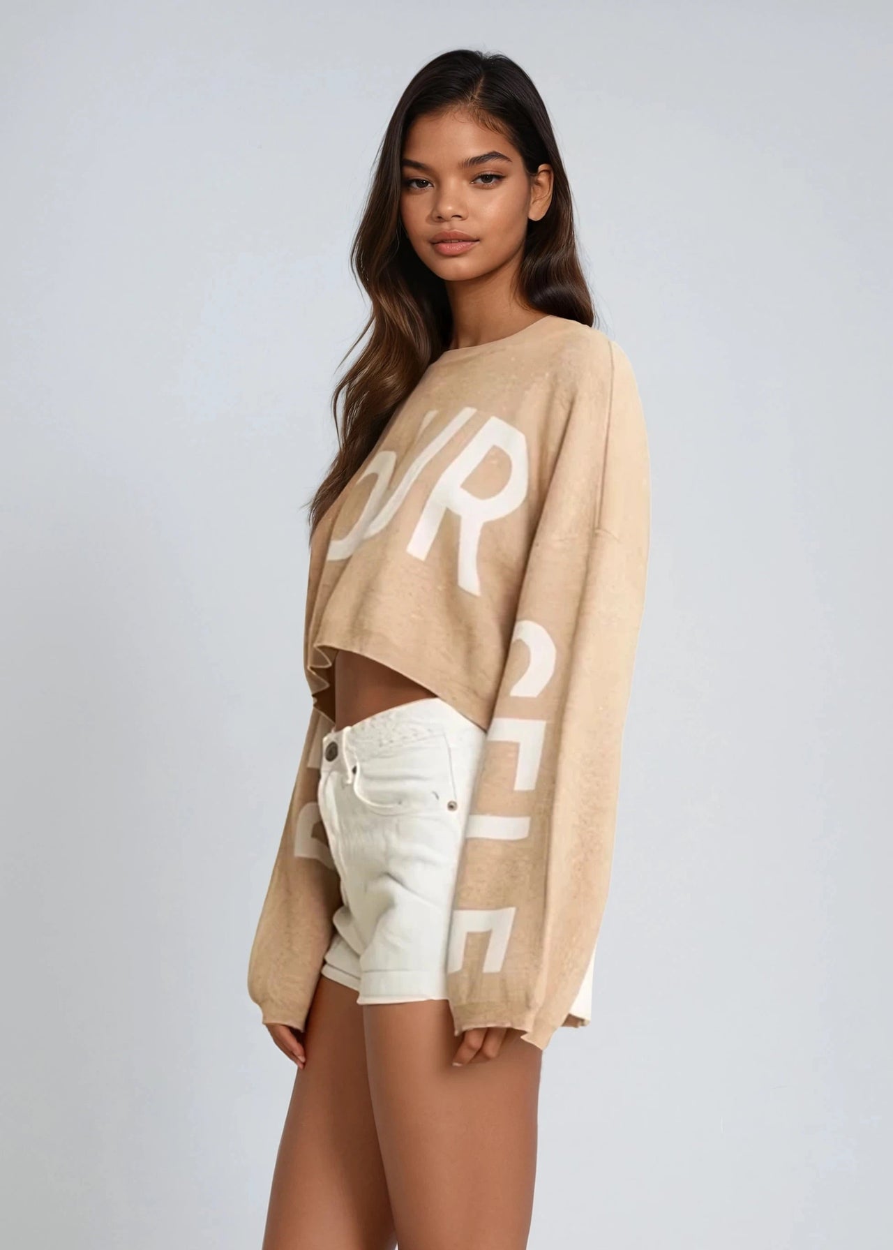 Woman wearing a beige Pink Seal sweater with text and white shorts on a light gray background