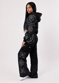Thumbnail for A model wearing a black cropped hoodie and matching wide-leg pants, both decorated with intricate silver rhinestone mandala patterns, posed against a light gray studio background.