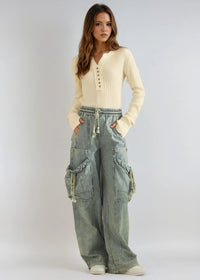 Thumbnail for Woman wearing a cream sweater and light blue cargo pants on a white background