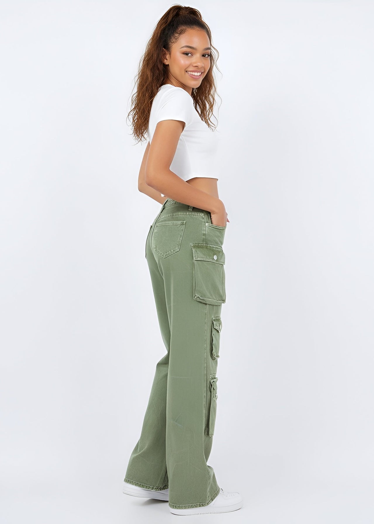 Woman wearing Pink Seal green cargo pants and a white top on a white background