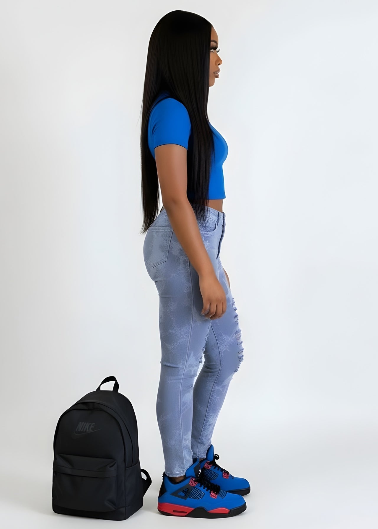 Person wearing a blue top and jeans with a black backpack on a white background