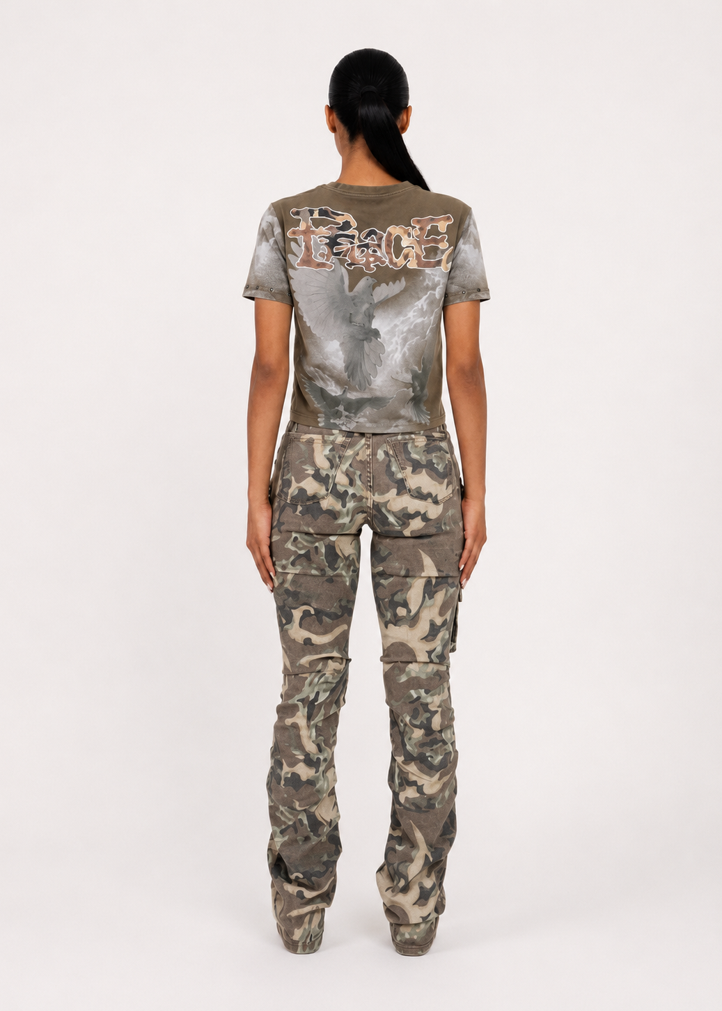 A model viewed from the back wearing a matching camouflage set consisting of a short-sleeve t-shirt with a large graphic print on the back and high-waisted cargo pants.