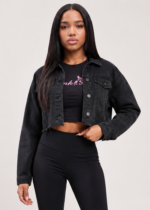 A woman modeling a black denim jacket, black cropped tank top with a pink 