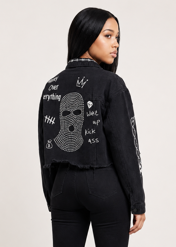 A model shown from the back wearing a black frayed denim jacket with white graphic text and a rhinestone skull design on the back