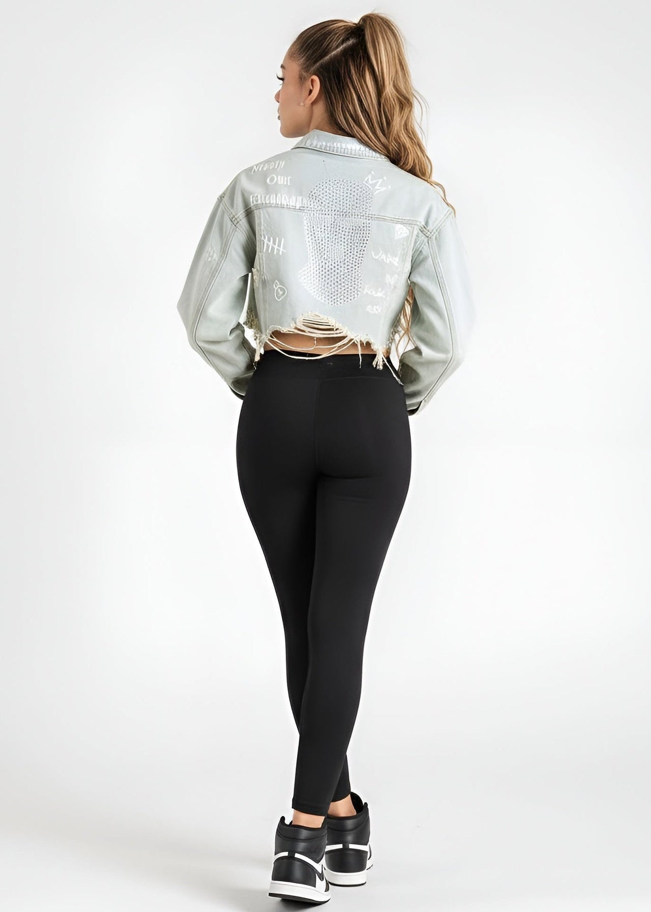 Person wearing a Pink Seal light blue crop denim jacket, black leggings, and black sneakers on a white background
