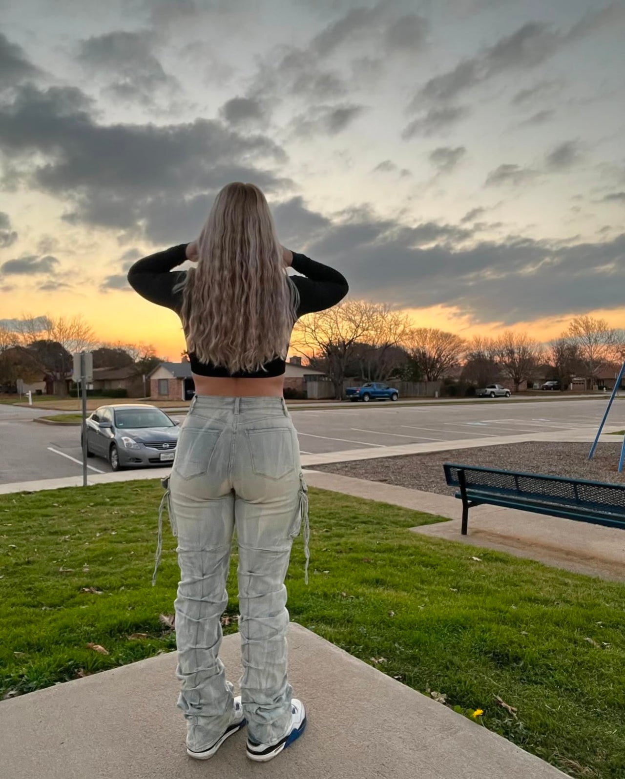 Person standing on a sidewalk looking at a cloudy sky