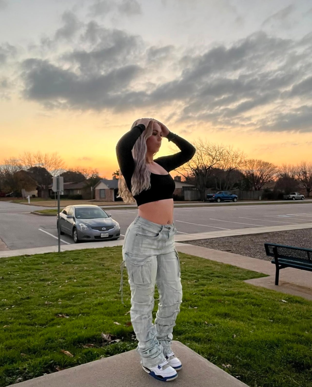 Person standing on a sidewalk with a sunset or sunrise sky in the background