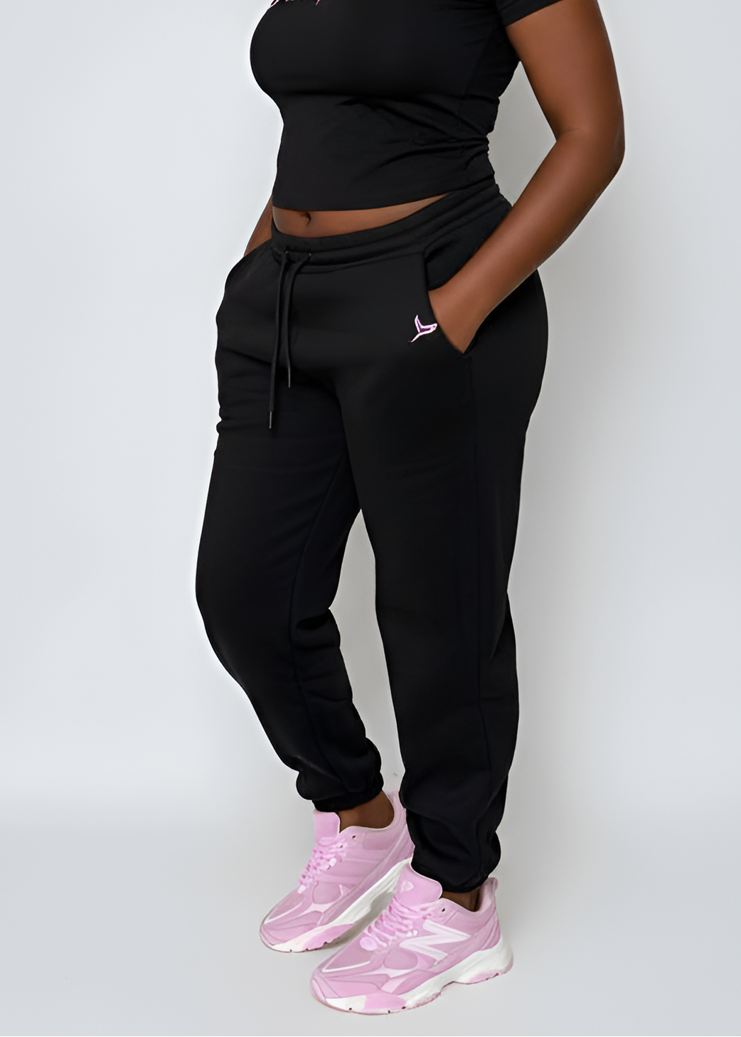 chic Pink Seal black jogger pants and pink sneakers on a white background