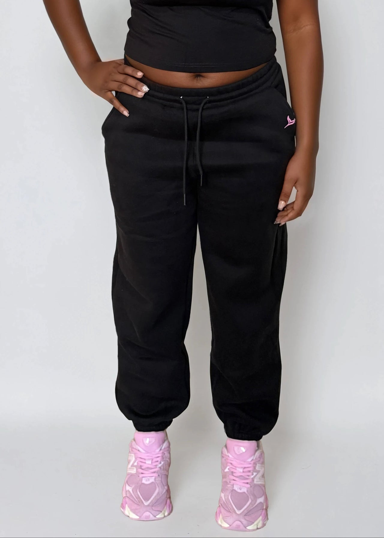Woman wearing a black crop top and black sweatpants with 'Pink Seal' logo on a white background