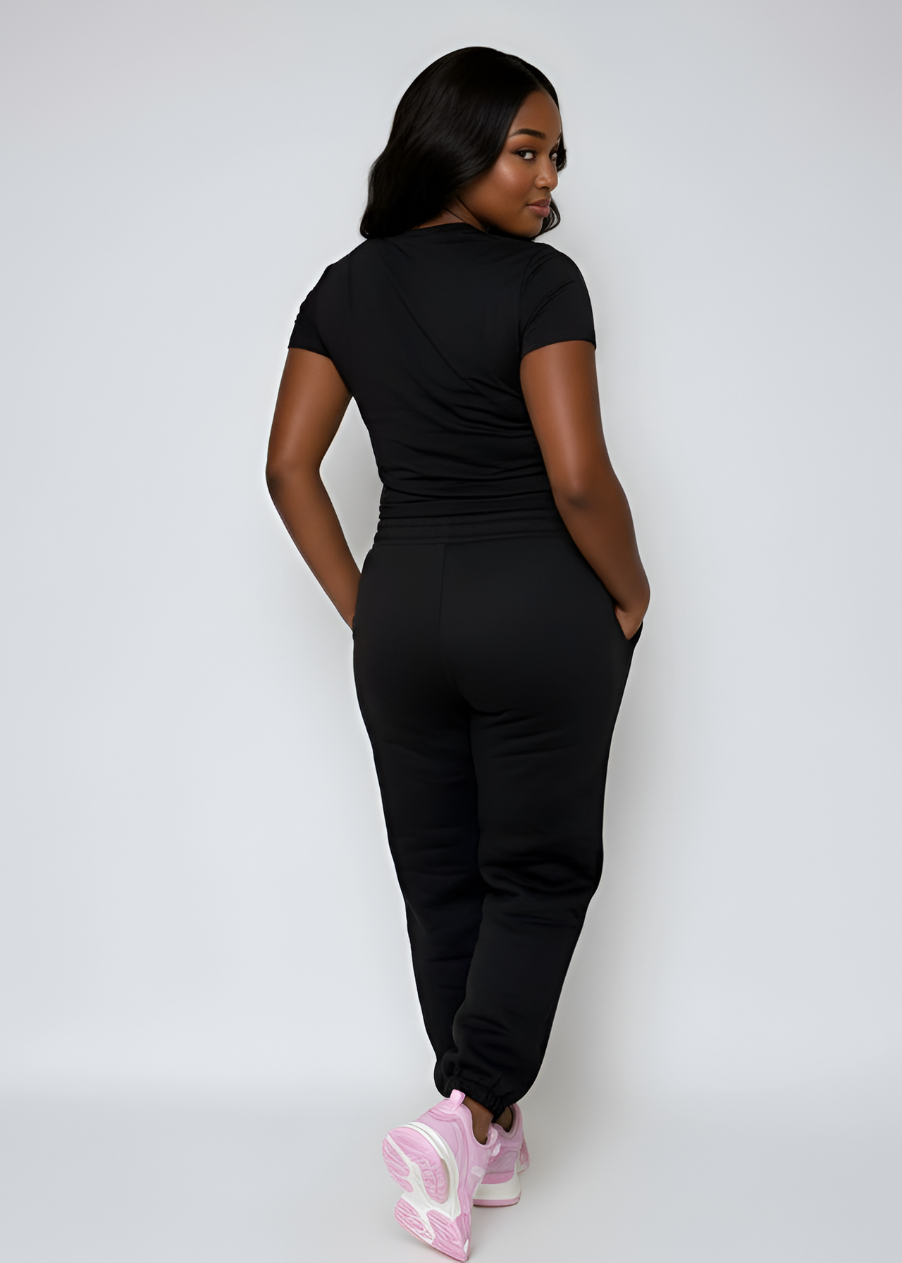 Woman wearing a black outfit with pink shoes on a white background