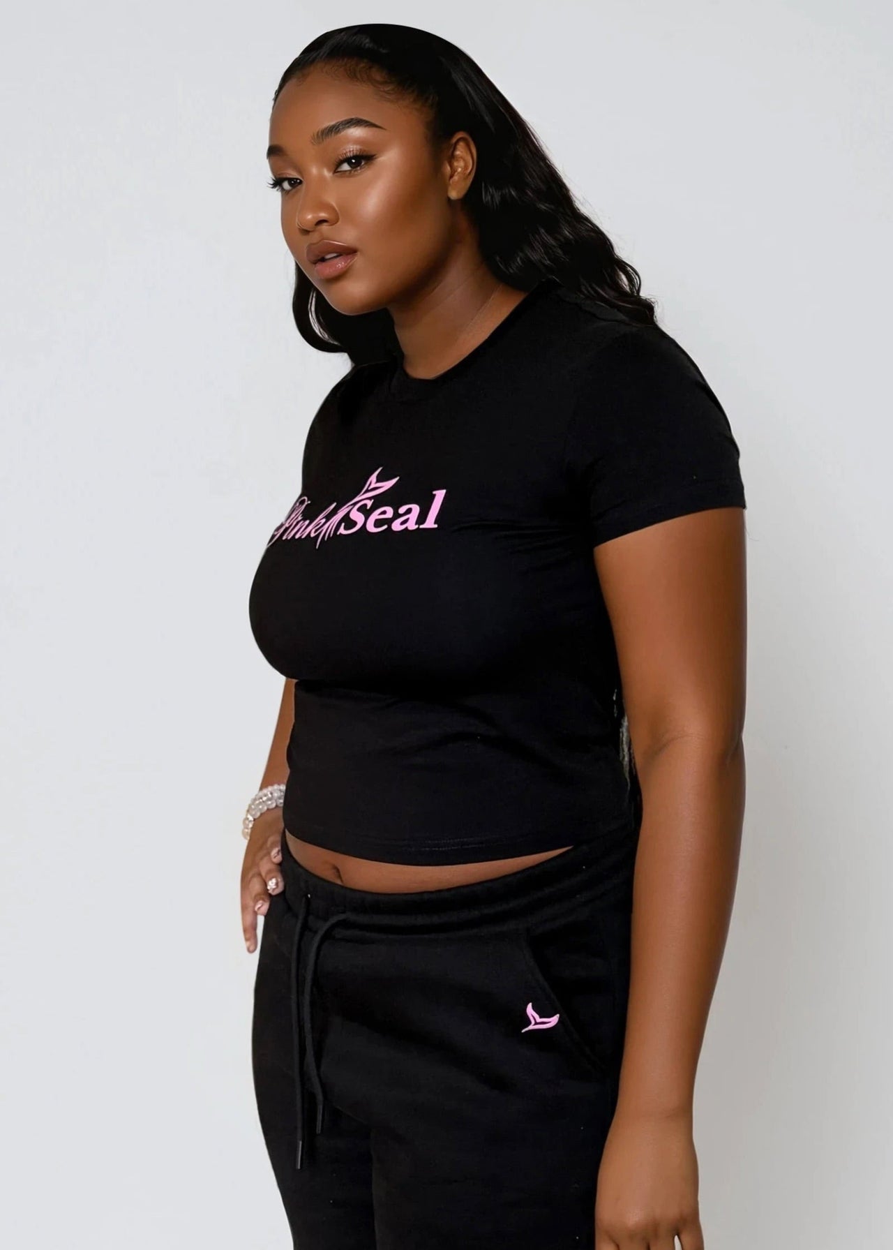 Woman wearing a black crop top with 'Pink Seal' branding with puff printing