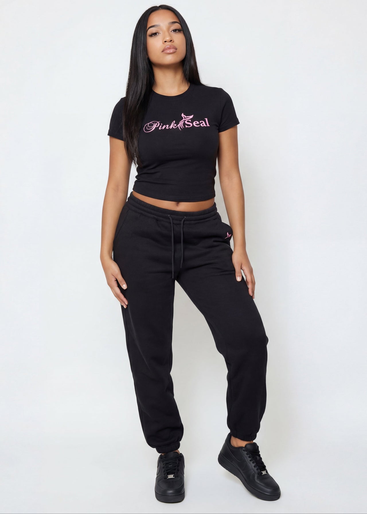 Woman wearing a black crop top with 'Pink Seal' branding. 
