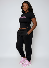 Thumbnail for Woman wearing a black Pink Seal joggers outfit with pink accents on a white background