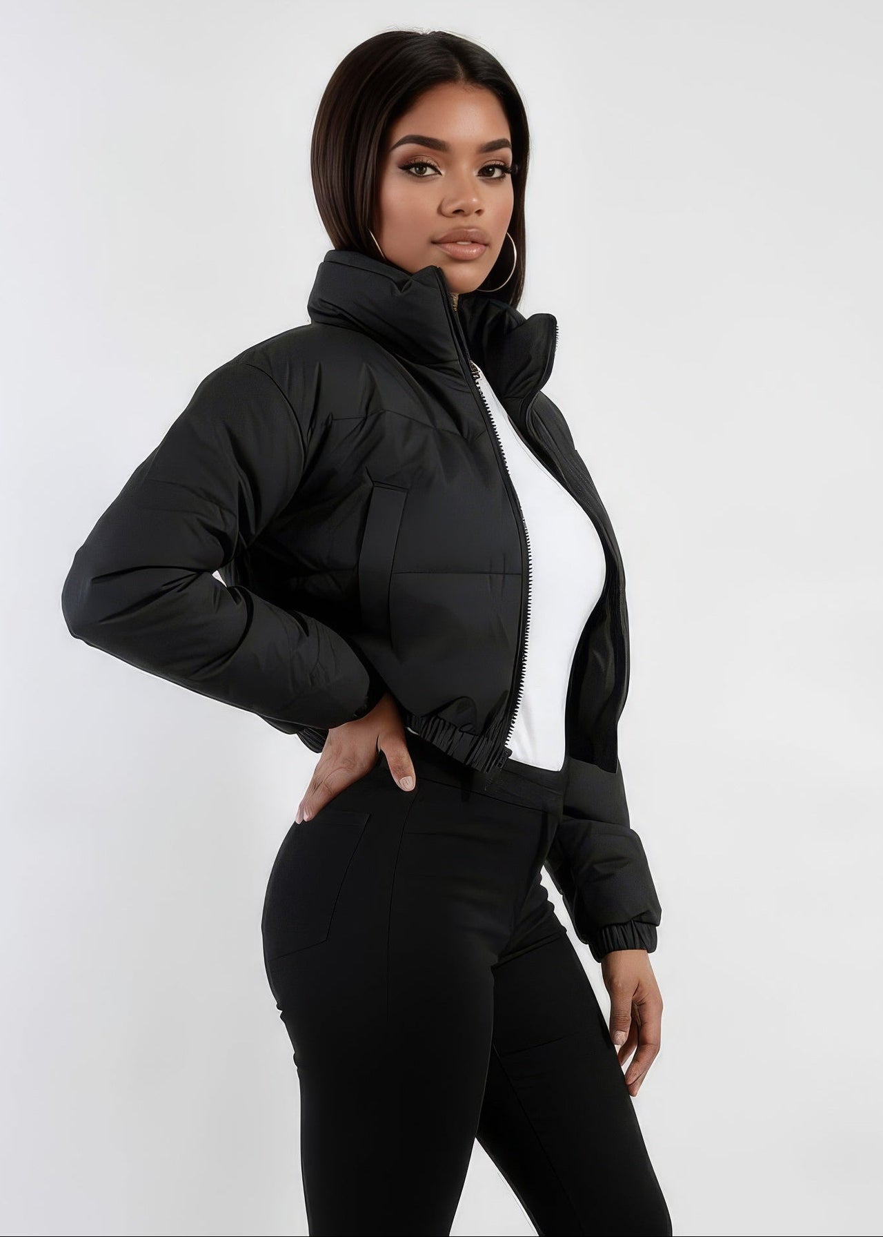Woman wearing a Pink Seal black puffer winter down jacket and black pants on a white background