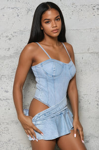 Thumbnail for Woman wearing a light blue denim dress against a gray concrete wall