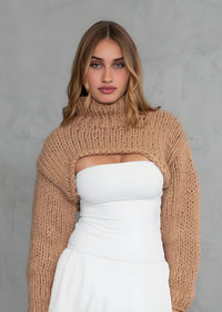 Thumbnail for Woman wearing a beige sweater over a white top and skirt against a gray background