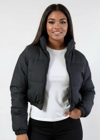 Thumbnail for Woman wearing a black puffer Winter down jacket over a white shirt on a white background