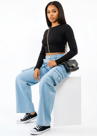 Thumbnail for Woman wearing a black long-sleeve top and Pink Seal light blue cargo pants, holding a black handbag on a white background.