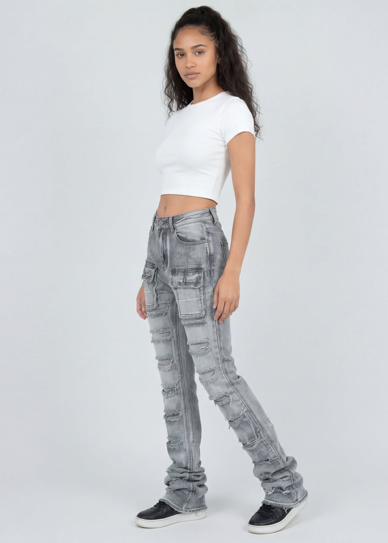 Woman wearing light grey jeans and a white top on a white background