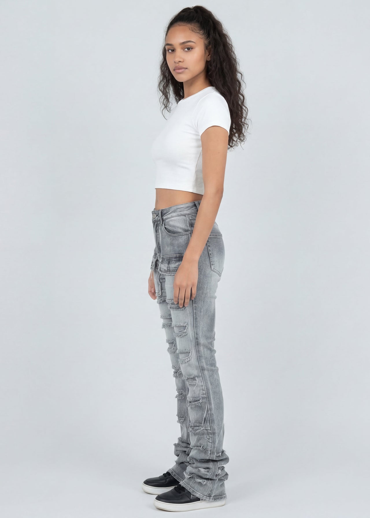 Woman wearing light grey jeans and a white top on a white background
