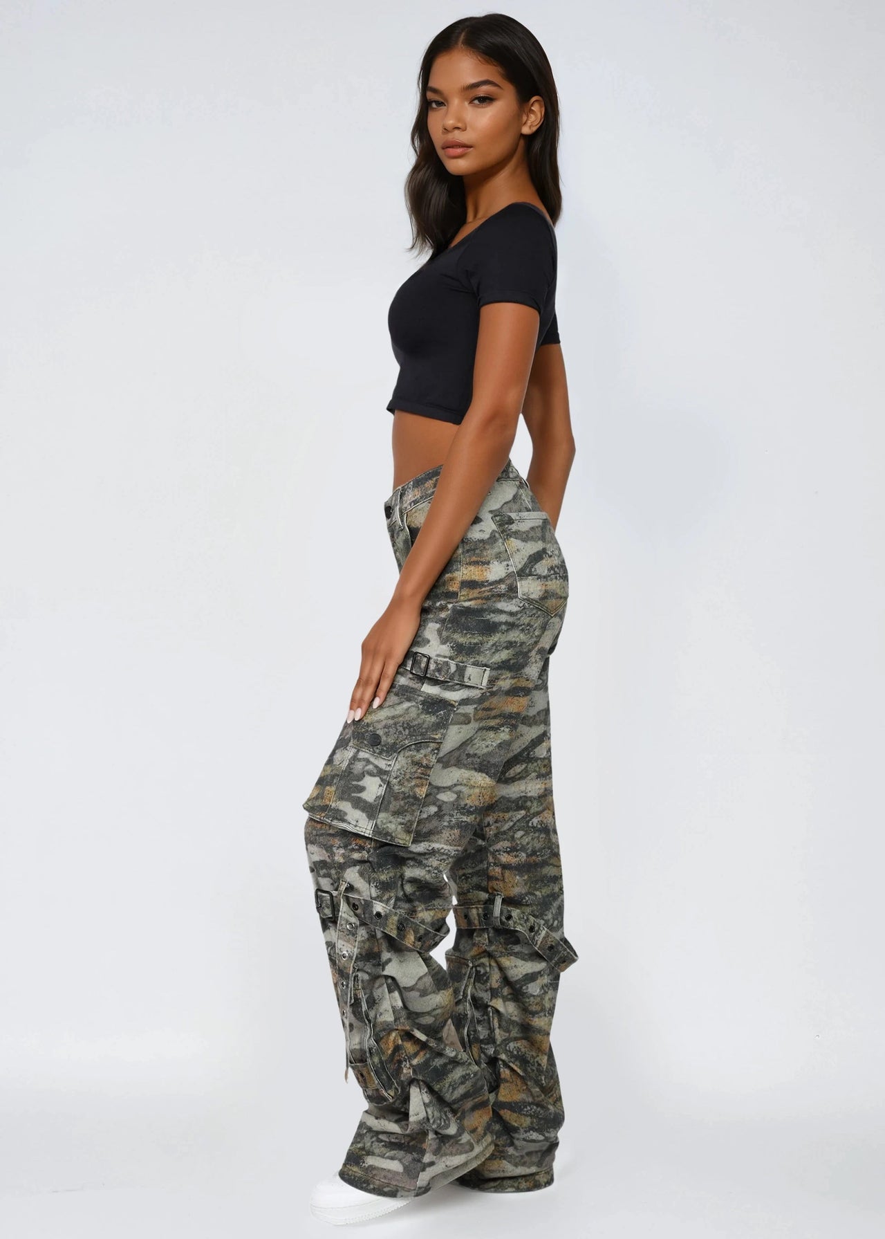 Woman wearing camouflage pants and a black top on a white background
