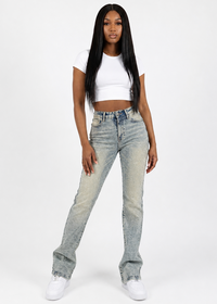 Thumbnail for A woman modeling a pair of light-wash, high-rise flare jeans with a faded wash, styled with a white crop top and white sneakers against a plain white studio background.
