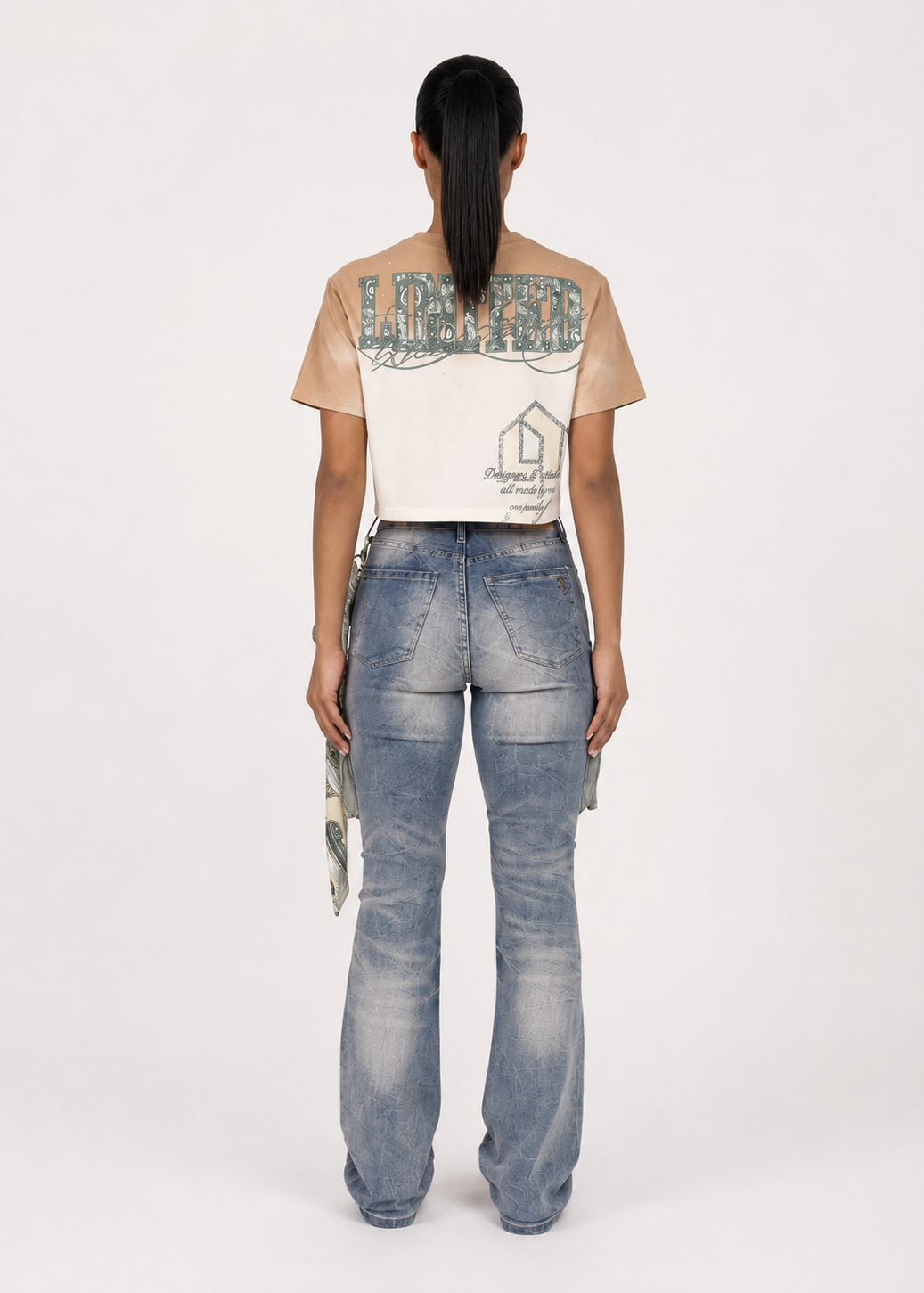 A model shown from the back wearing a beige and white graphic t-shirt and light-wash blue jeans with cargo pockets, against a plain white studio background.