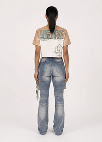 Thumbnail for A model shown from the back wearing a beige and white graphic t-shirt and light-wash blue jeans with cargo pockets, against a plain white studio background.