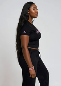Thumbnail for Woman wearing a black crop top & jogger pants set with 'Pink Seal' branding puff print